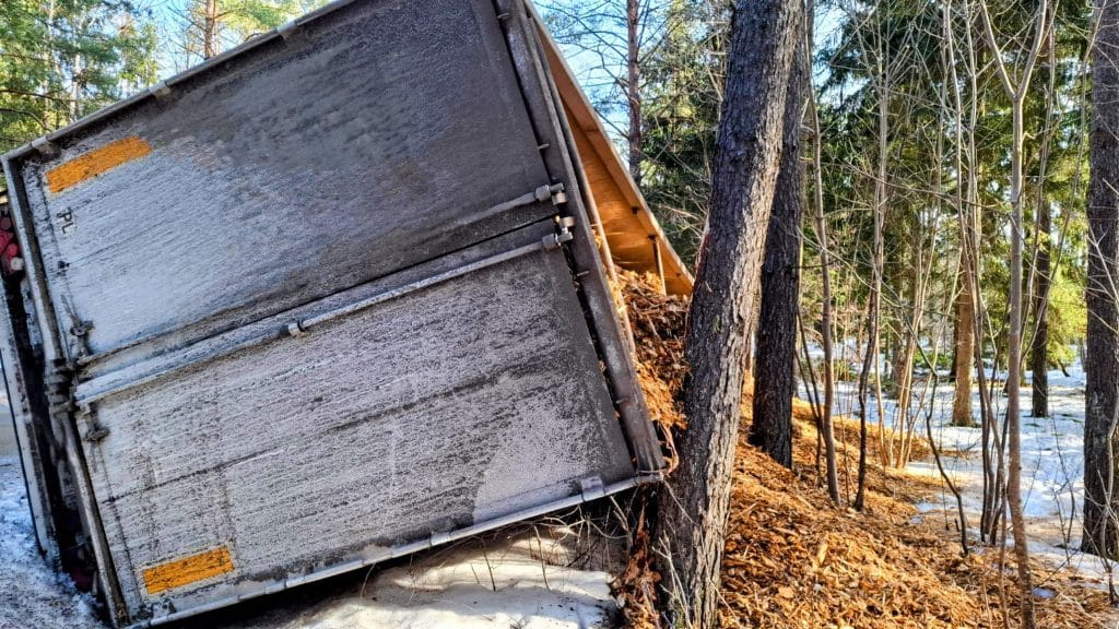 Ciężar&oacute;wka w rowie obok drzew na zaśnieżonej drodze, widoczna z boku, w pobliżu Pisza.