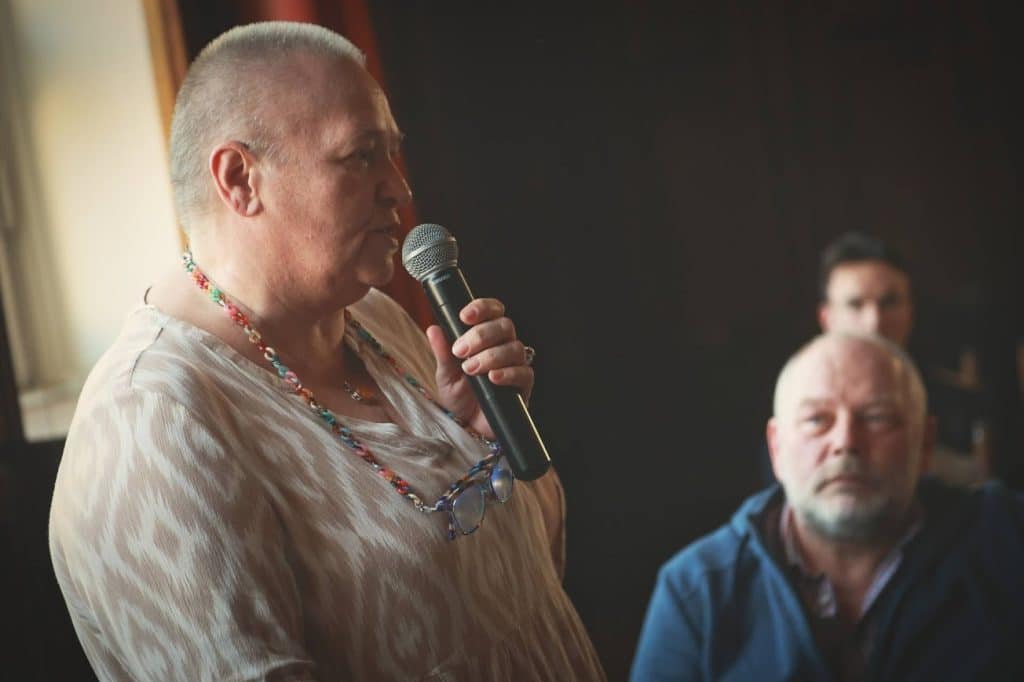 Kobieta przemawia do zgromadzonych podczas spotkania organizacji społecznych w Olsztynie.