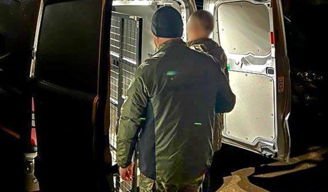 Funkcjonariusze Straży Granicznej wyprowadzają cudzoziemc&oacute;w z pojazdu w nocy.