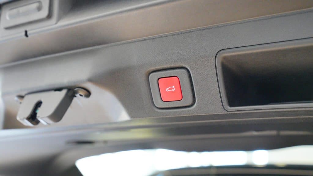 Przycisk otwierania bagażnika w samochodzie, widoczny na tle wnętrza auta.
