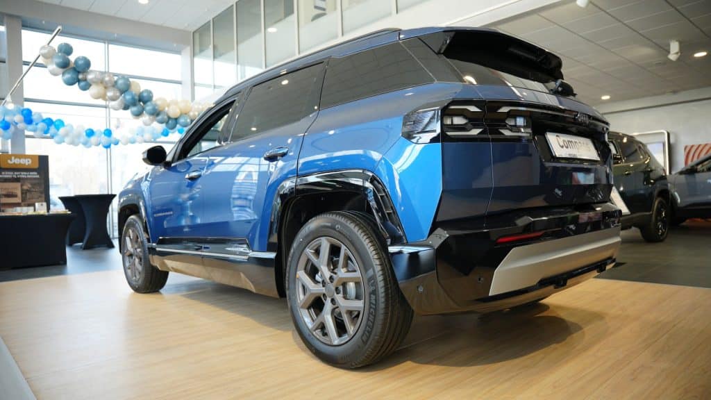 Nowy Jeep Compass w salonie samochodowym, w kolorze niebieskim, z nowoczesnym designem i dużym prześwitem.