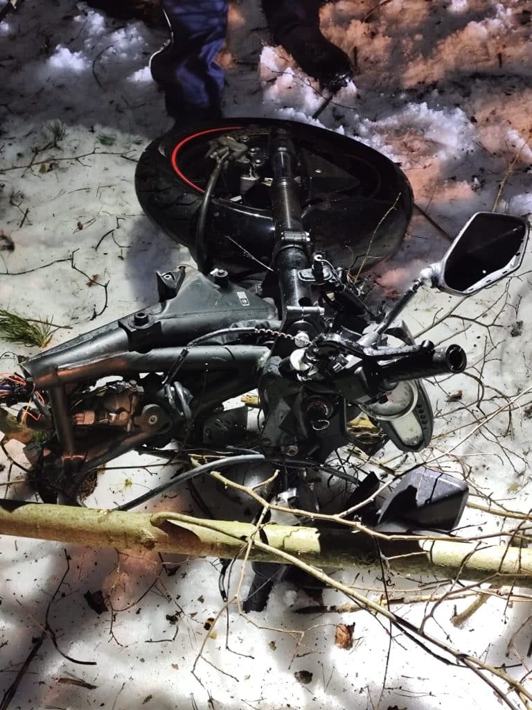 Rozbity motocykl na śniegu po wypadku na drodze wojew&oacute;dzkiej.