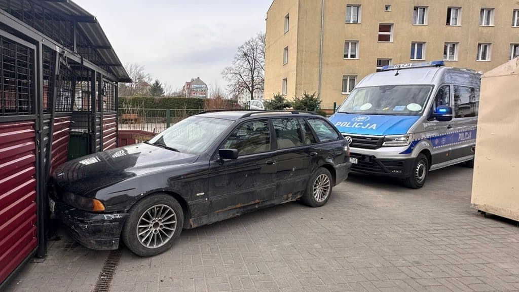 Uszkodzony czarny samoch&oacute;d i radiow&oacute;z na osiedlu, po pościgu ulicami miasta.