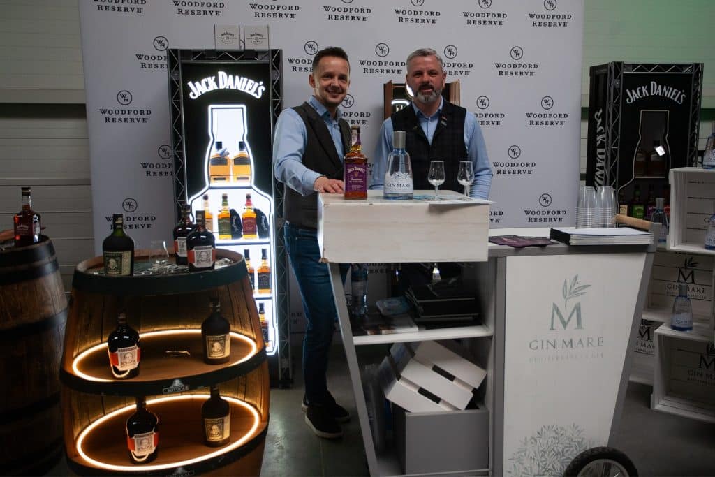 Stoiska targowe z alkoholem i przedstawiciele na tle logo wydarzenia w Gdańsku.