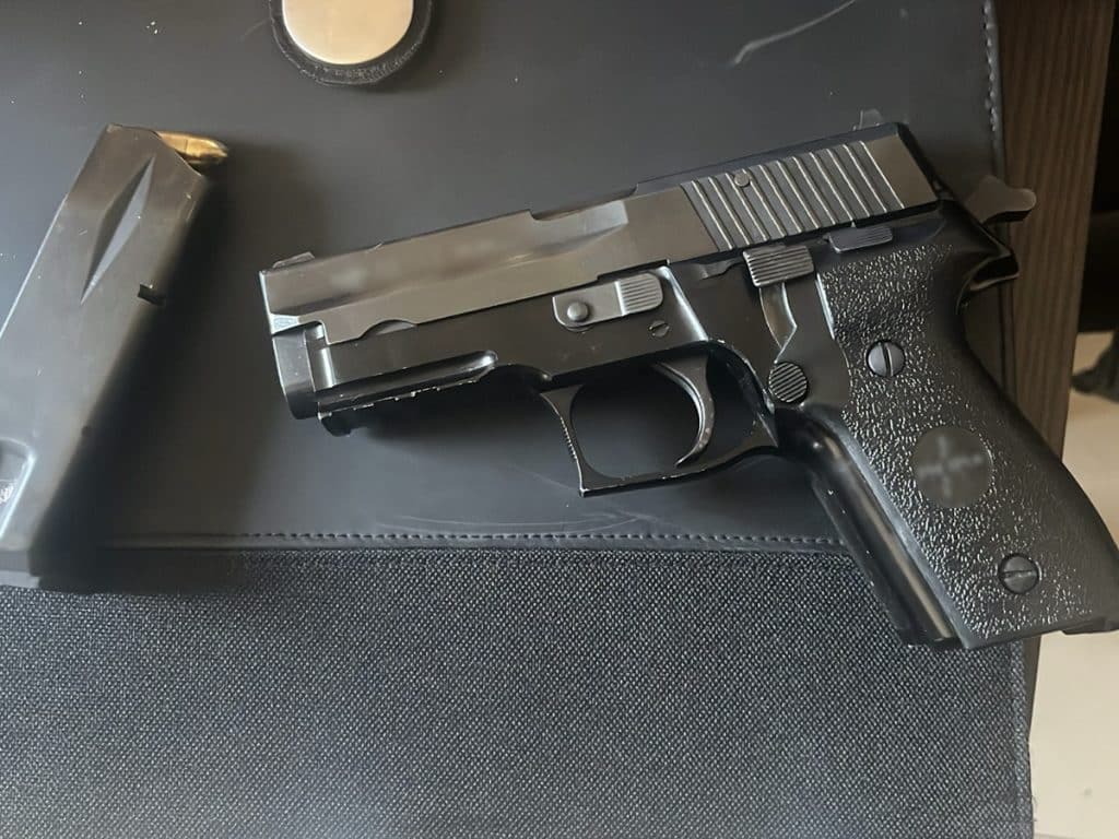 Pistolet na czarnym tle, obok metalowy magazynek, na ciemnym tle.