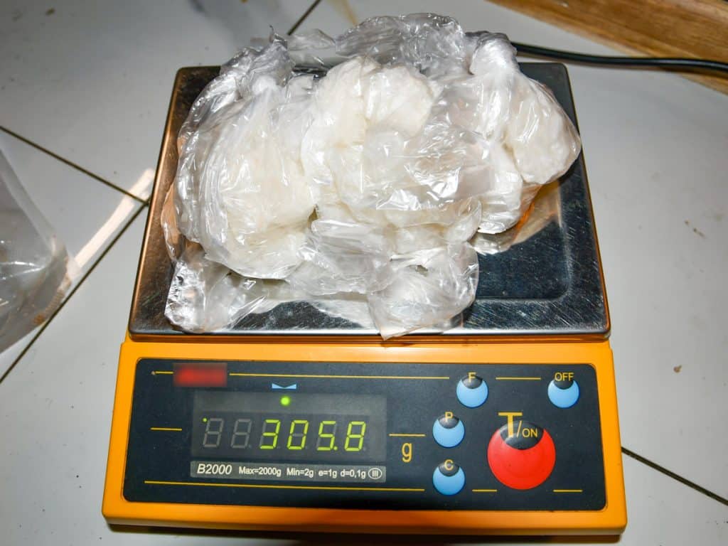 Na wadze leży pakiet nielegalnego towaru, prawdopodobnie narkotyk&oacute;w, w plastikowym opakowaniu.