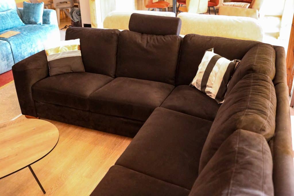 Fotel i sofa w salonie meblowym podczas wyprzedaży, w tle inne meble i lampy.