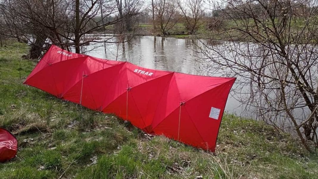 Ciało mężczyzny odnalezione w rzece Pisa na Mazurach, widok na miejsce zdarzenia z czerwonymi parasolami strażak&oacute;w.