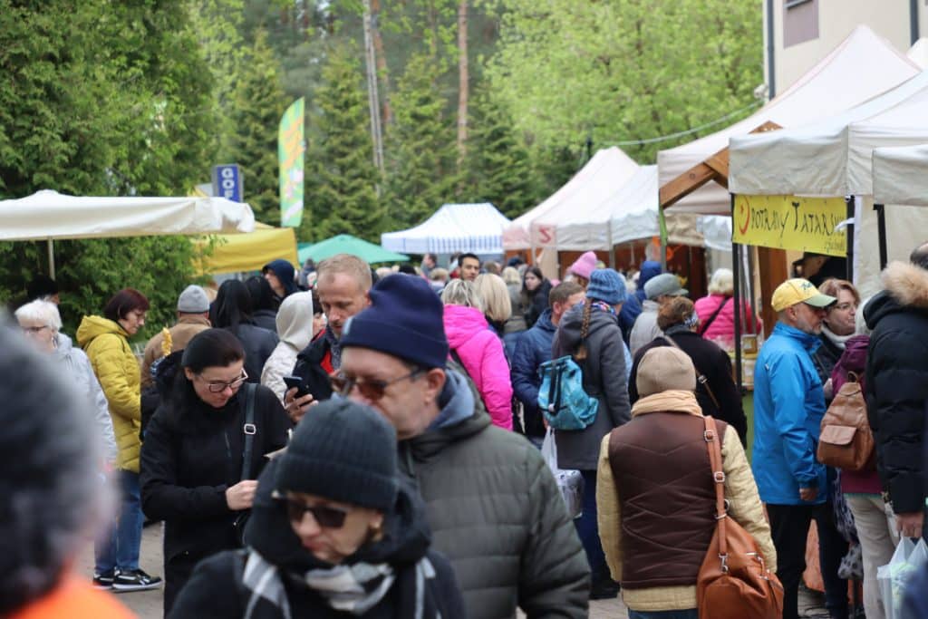 Tłum ludzi na targach ogrodniczych w Olsztynie, stoiska z roślinami i produkty ogrodnicze.