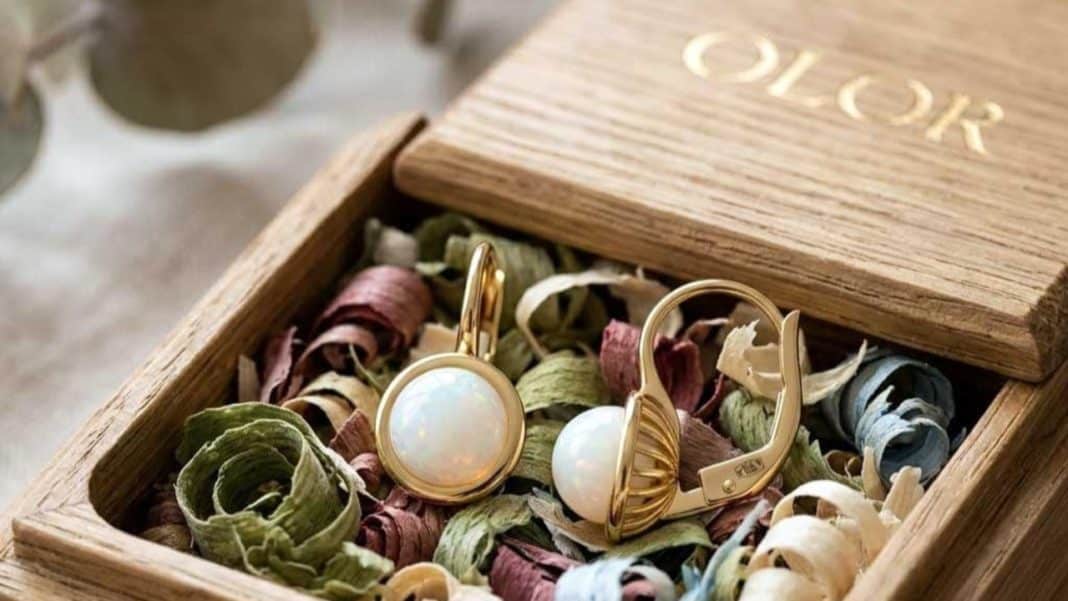 Złote i srebrne biżuterie w drewnianym pudełku z kolorowymi suszonymi kwiatami.