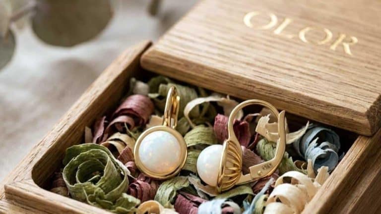 Złote i srebrne biżuterie w drewnianym pudełku z kolorowymi suszonymi kwiatami.