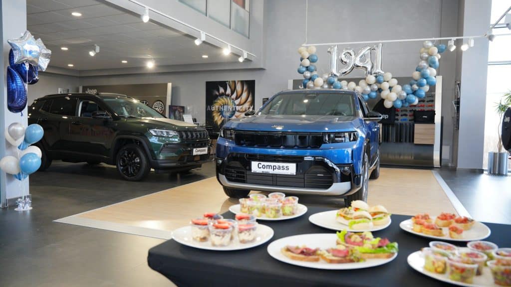 Nowy Jeep Compass na wystawie w salonie samochodowym, dekoracje i przekąski na tle modeli.