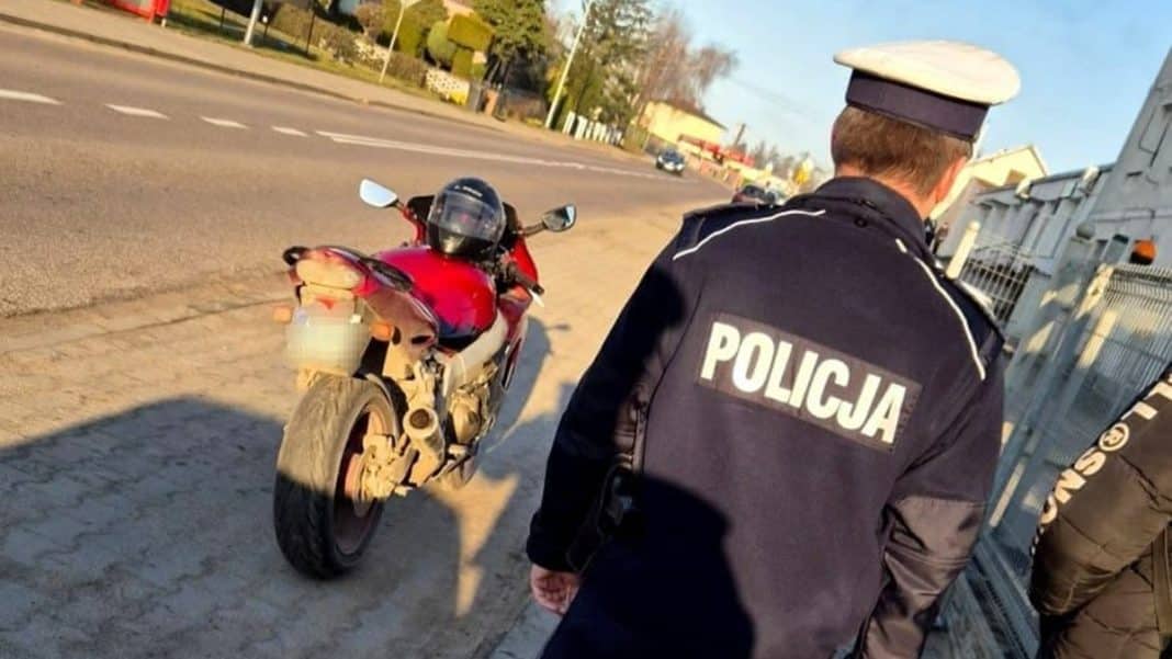 Policjant zatrzymuje czerwony motocykl Kawasaki na ulicy w Marzęcicach.