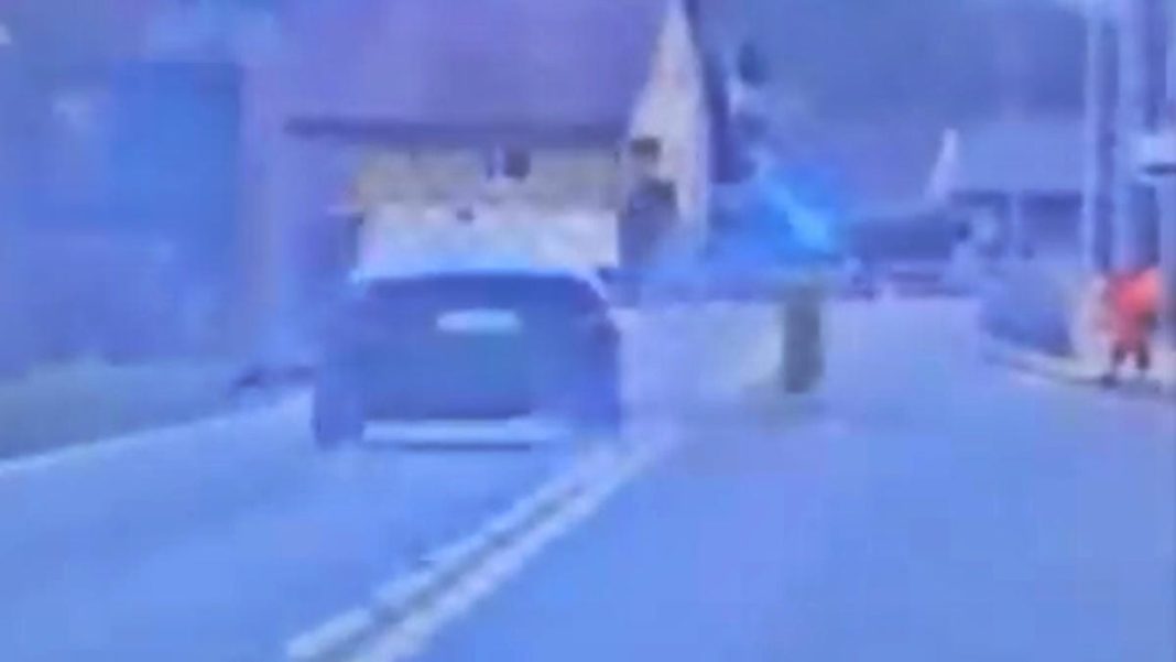 Zdjęcie przedstawia samoch&oacute;d na drodze, prawdopodobnie podczas pościgu policyjnego.