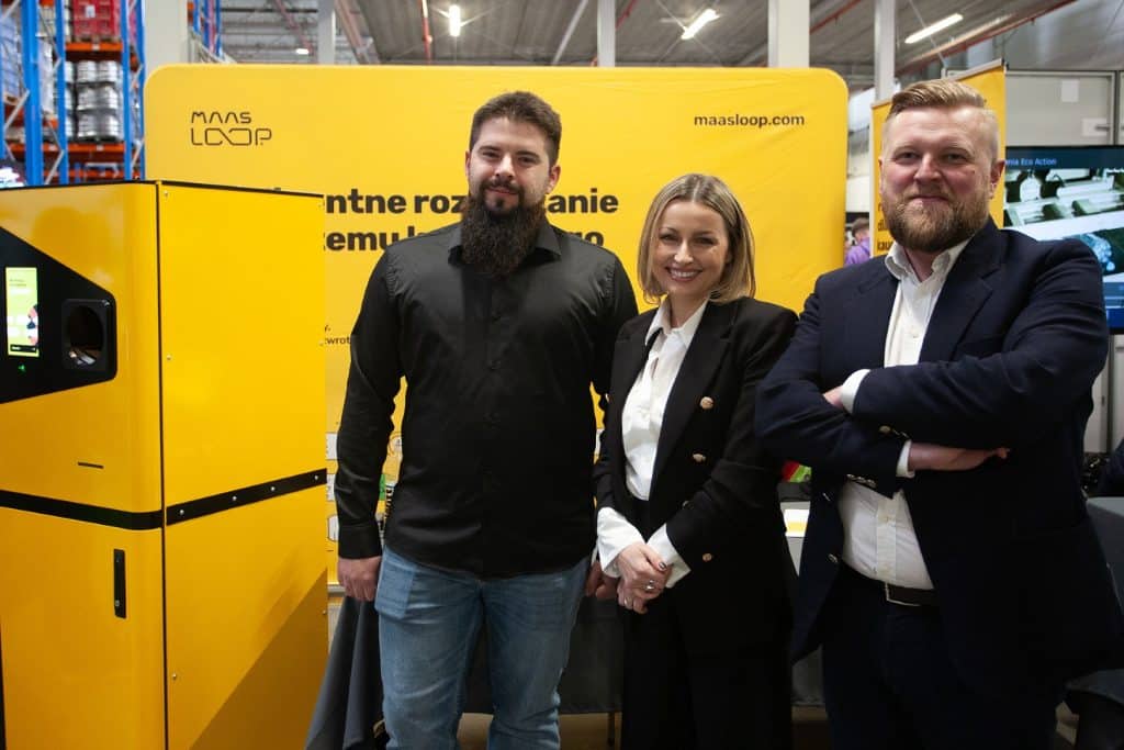 Trzy osoby na targach biznesowych w Gdańsku, stoją obok stoisk z branży HoReCa i handlu.