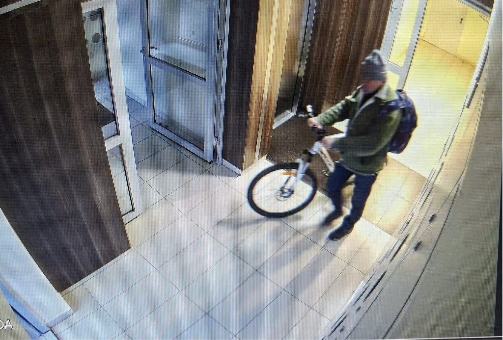 Mężczyzna na rowerze wchodzący do klatki schodowej bloku, nagranie z monitoringu.