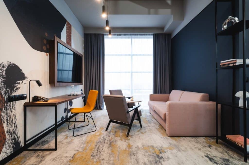 Wnętrze nowoczesnego hotelu z komfortowym salonem, dużym oknem i stylowym wystrojem.