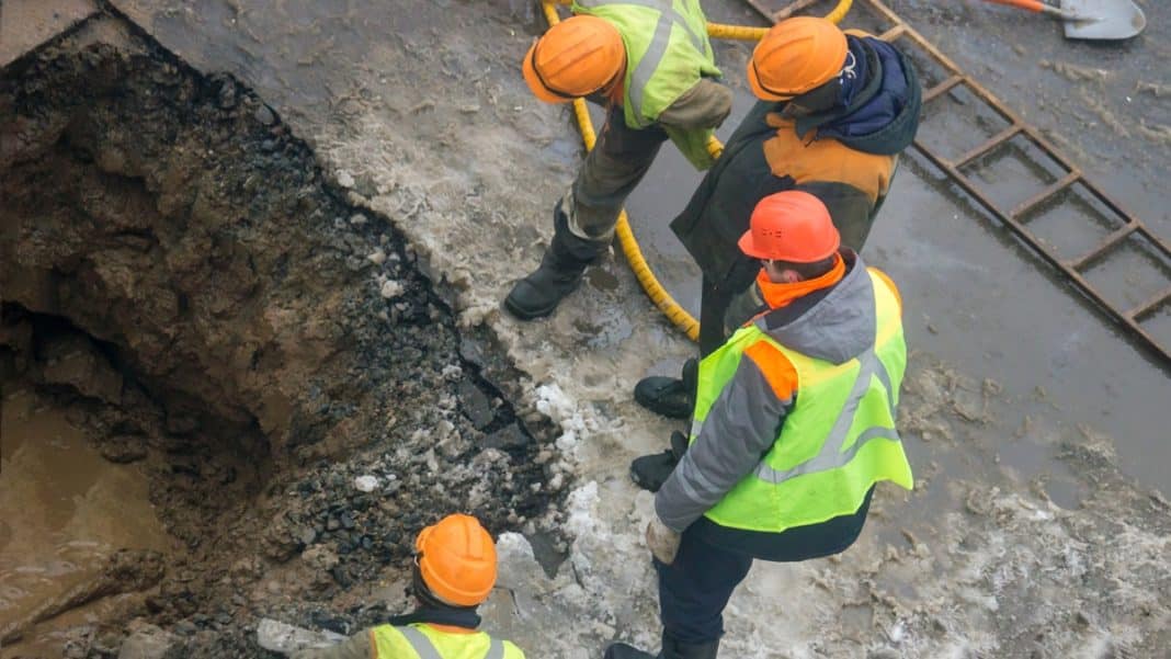 Pracownicy służb ratunkowych badają głęboką wyrwę w jezdni na ulicy Mrongowiusza w Olsztynie.