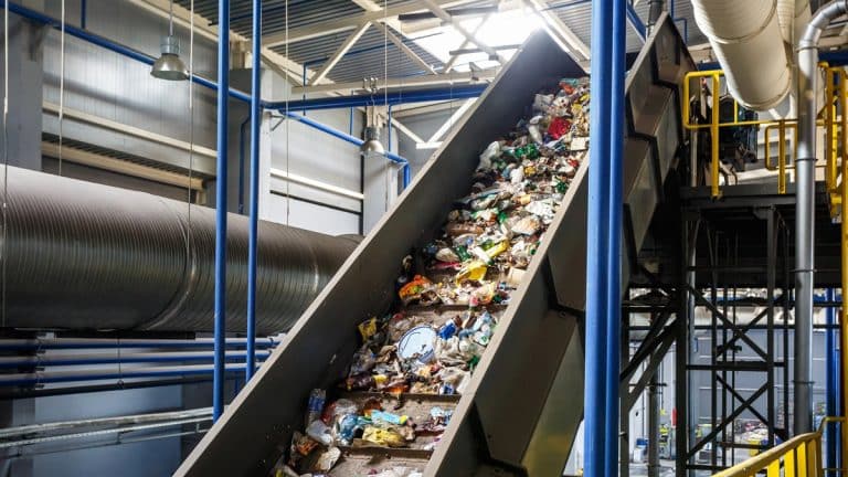 Transport odpad&oacute;w w zakładzie utylizacji, na taśmie przesypują się śmieci.