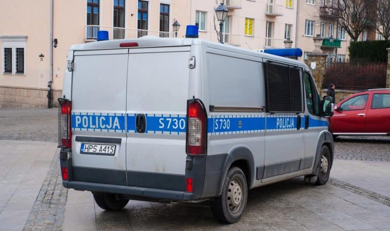 Policja na ulicy Ostr&oacute;dy, widoczny radiow&oacute;z policyjny z napisem 'Policja' na boku.