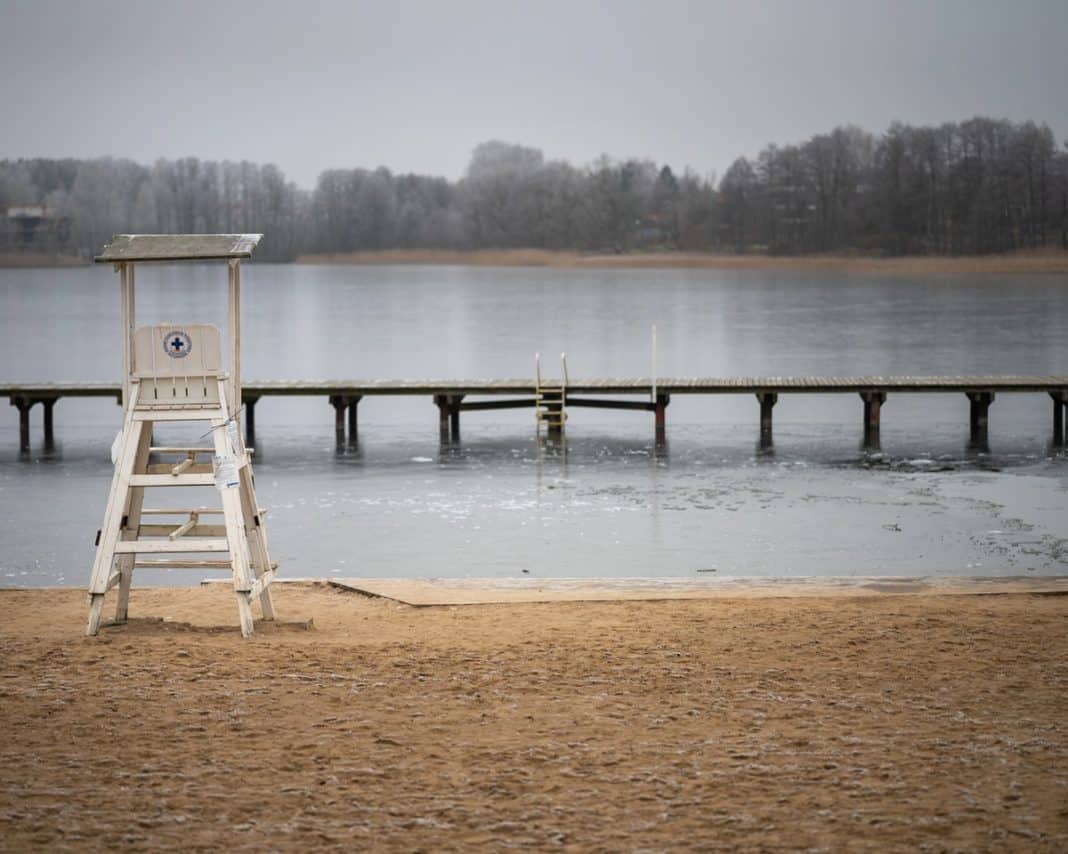 Pusta plaża nad jeziorem Ukiel z leżakiem ratownika i pomostem, zimowa sceneria, brak ludzi.