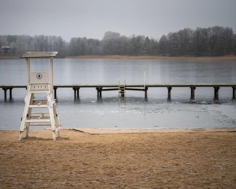 Pusta plaża nad jeziorem Ukiel z leżakiem ratownika i pomostem, zimowa sceneria, brak ludzi.