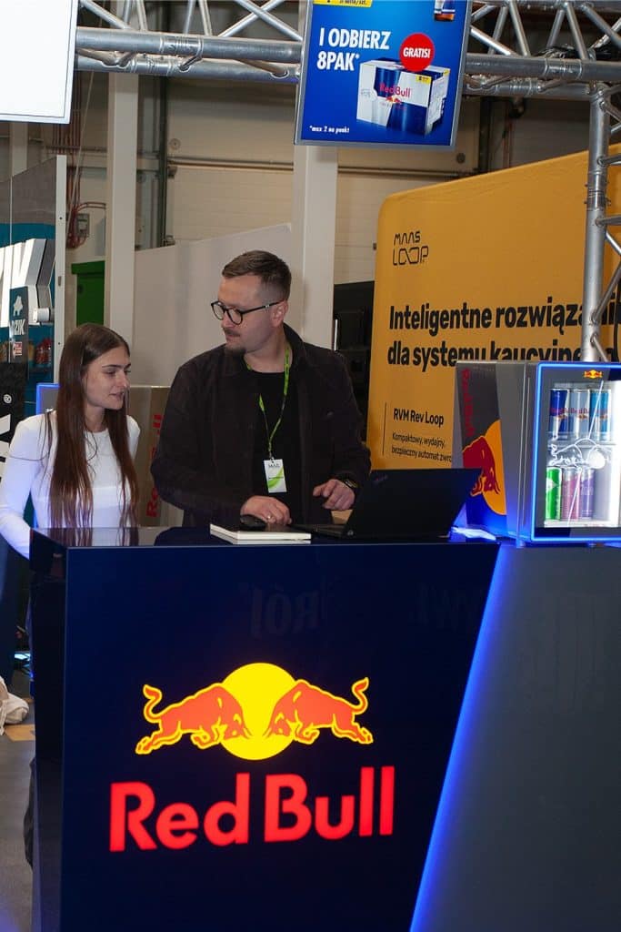 Uczestnicy rozmawiają przy stoisku Red Bull na targach w Gdańsku.