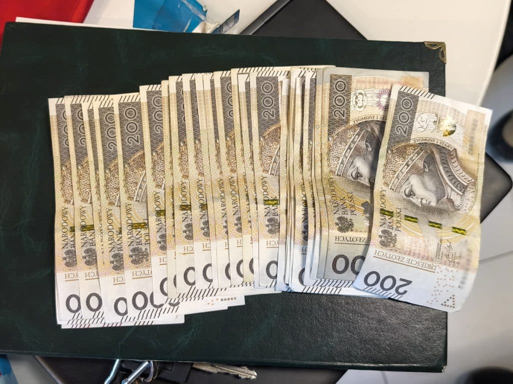 Na zdjęciu widoczna jest stosowna ilość banknot&oacute;w o nominale 200 zł, ułożonych na ciemnej powierzchni.
