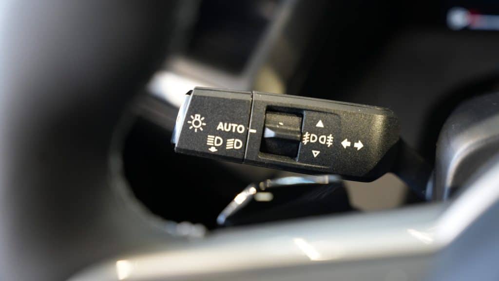 Przedni panel sterowania świateł i kierunkowskaz&oacute;w w samochodzie, z r&oacute;żnymi symbolami i przełącznikami.