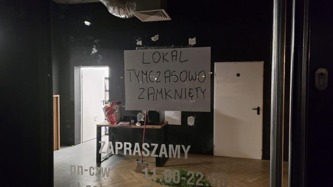 Widok zamkniętej restauracji w centrum Olsztyna z informacją na drzwiach o wstrzymaniu działalności.