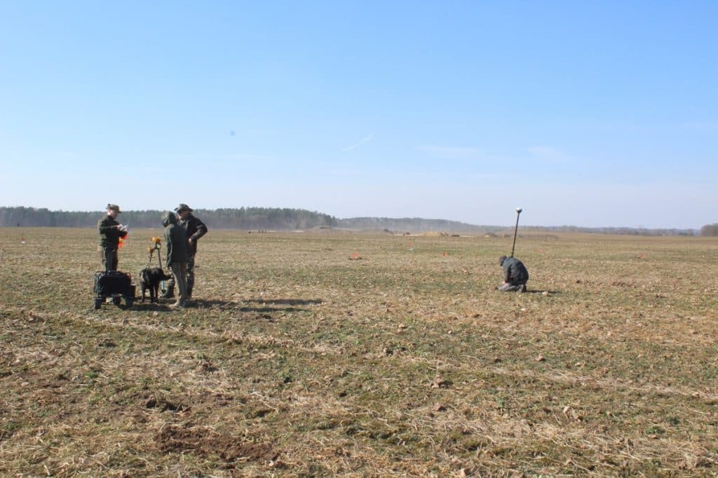 Archeolodzy prowadzą poszukiwania na polu w okolicach wsi Leszcz, w tle szeroka r&oacute;wnina i niebo.