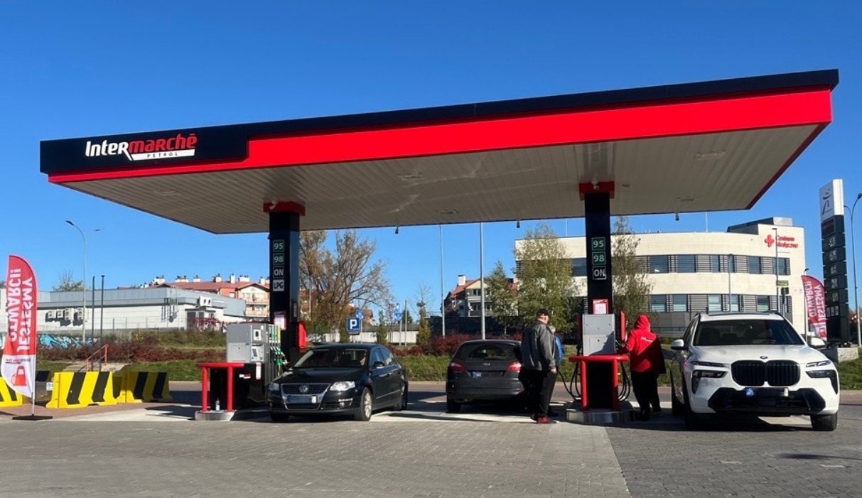 Stacja paliw Intermarch&eacute; Olsztyn z samochodami i klientami podczas tankowania.