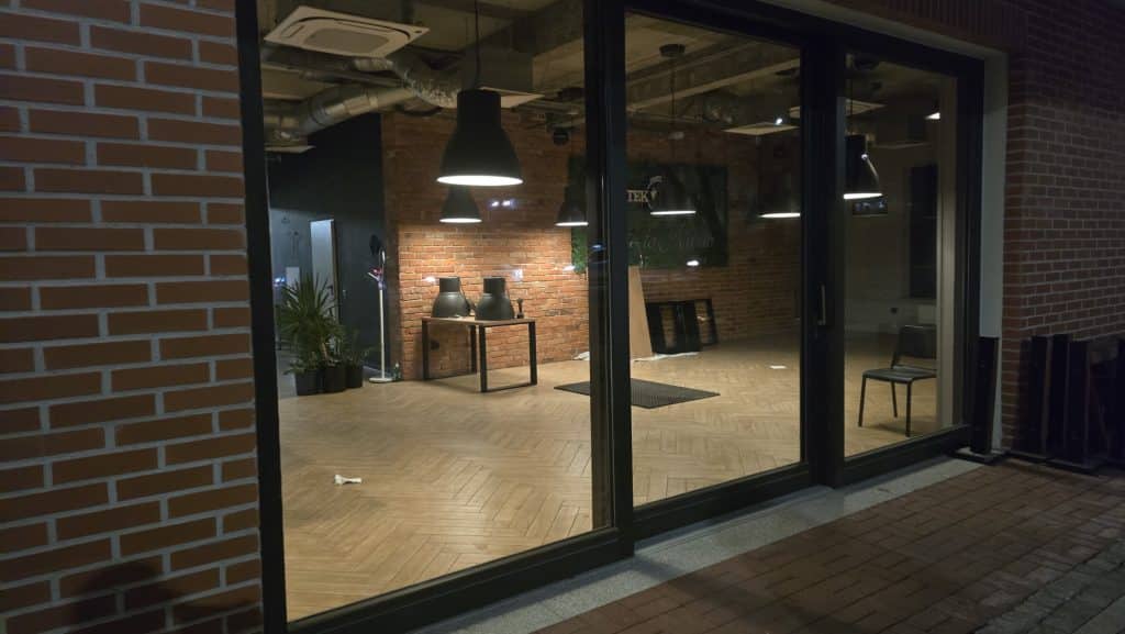 Widok zamkniętej restauracji z dużymi oknami i widocznym wnętrzem, puste stoliki i oświetlenie.