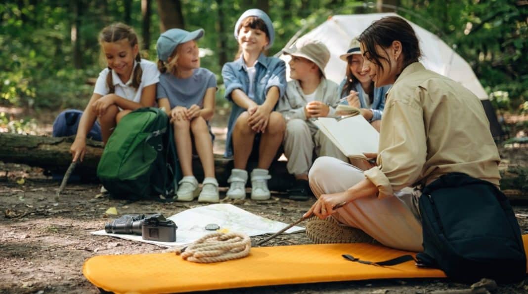 Wychowawca rozmawia z grupą dzieci podczas wycieczki na łonie natury.