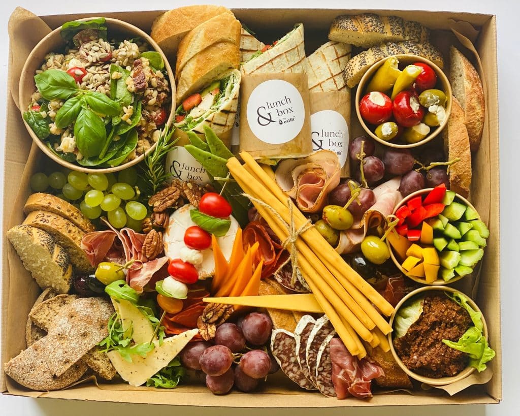 Duży box z r&oacute;żnorodnymi zdrowymi przekąskami, warzywami i serami, estetycznie podane.