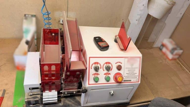 Urządzenie do produkcji papieros&oacute;w i zabezpieczone wyroby tytoniowe na stole.