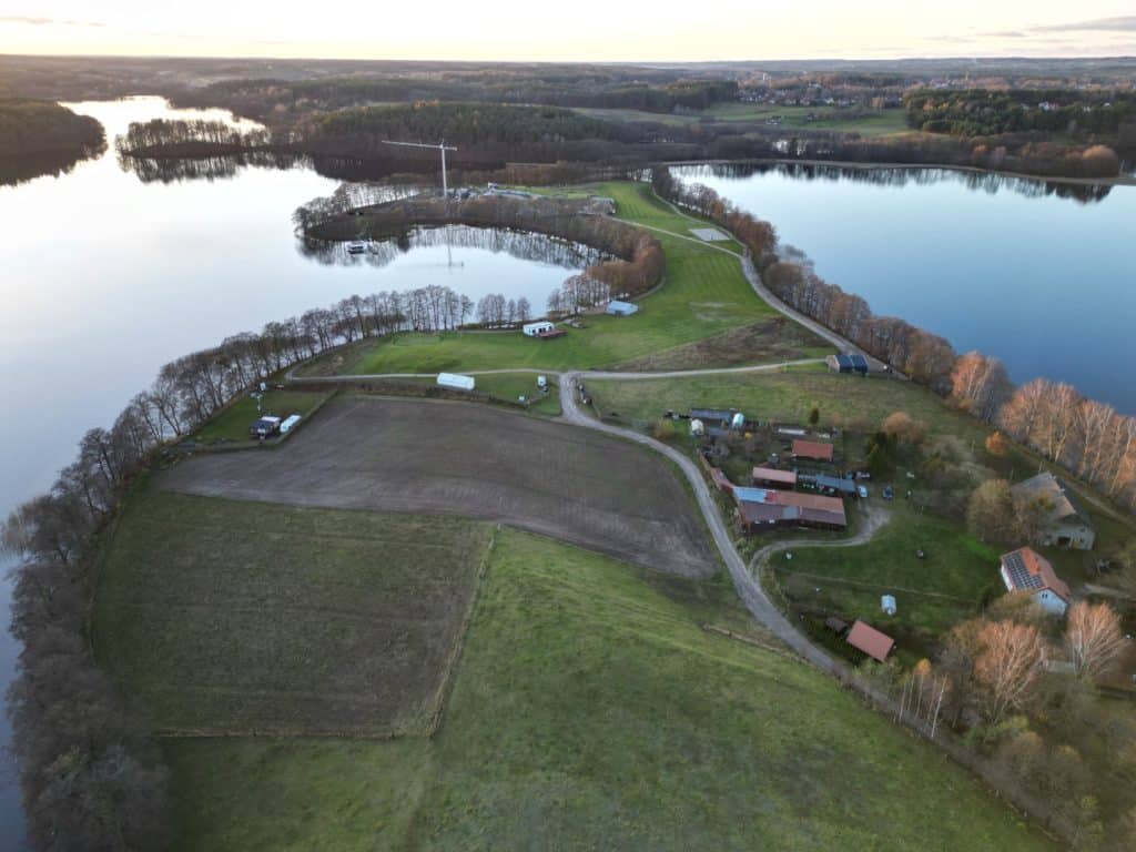 Widok z powietrza na jezioro Ukiel i otaczające je tereny, w tym zabudowę i zieleń.
