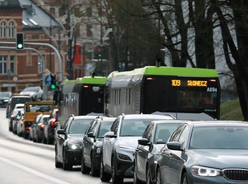 Korek samochodów na ulicy w Olsztynie, w tle autobus miejski.