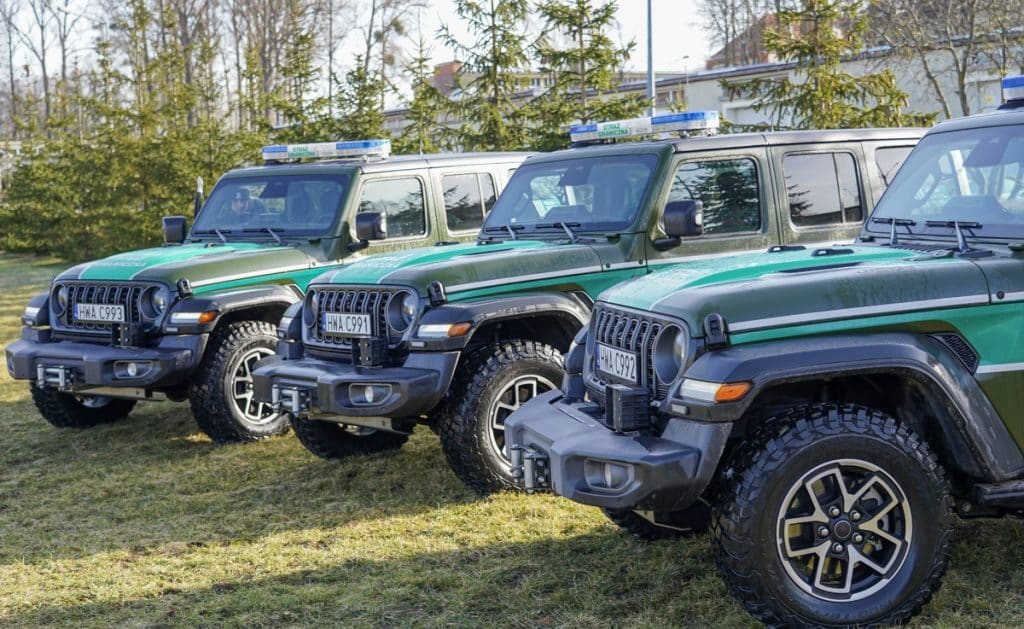 Trzy nowe samochody patrolowe Jeep Wrangler ustawione na trawie, gotowe do służby na granicy z Rosją.