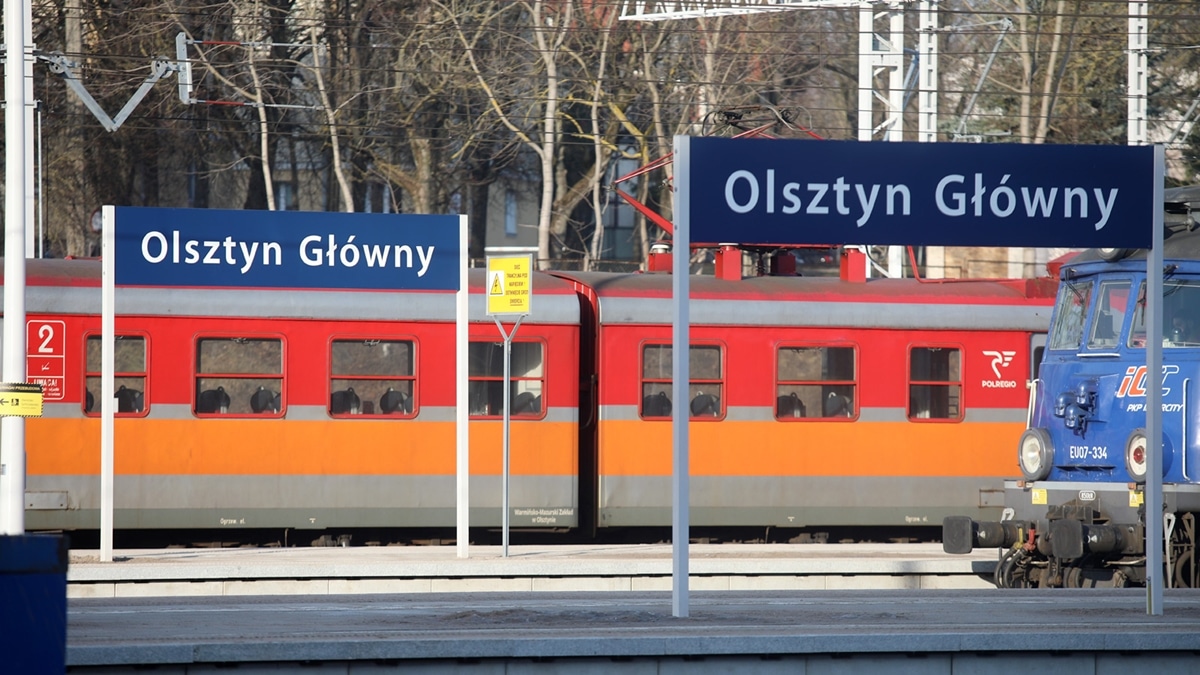 Pociąg POLREGIO na stacji Olsztyn Główny, widoczny z tablicami informacyjnymi.