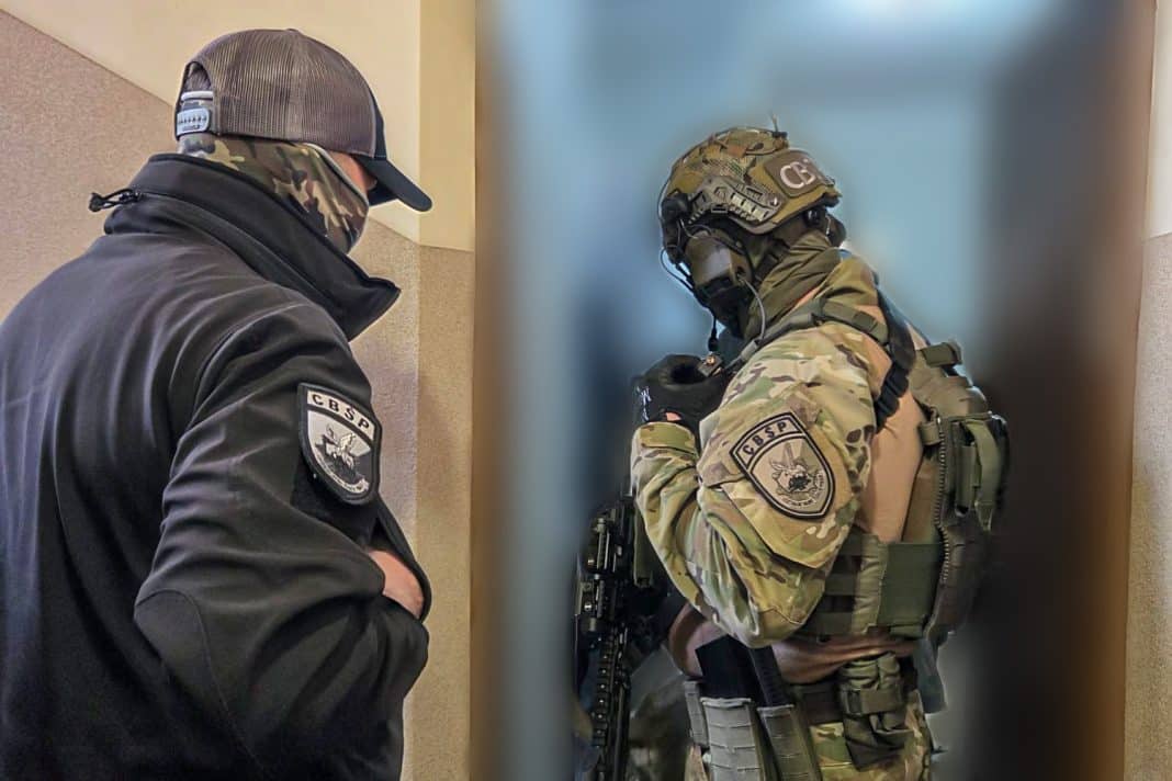 Funkcjonariusze CBŚP w kamizelkach i z bronią podczas akcji w budynku.