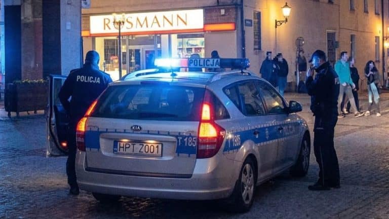 Policjanci zatrzymują samoch&oacute;d w centrum Olsztyna podczas kontroli drogowej wieczorem.