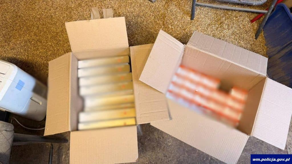 Otwarte kartony z nielegalnie wyprodukowanymi papierosami i tytoniem na podłodze.