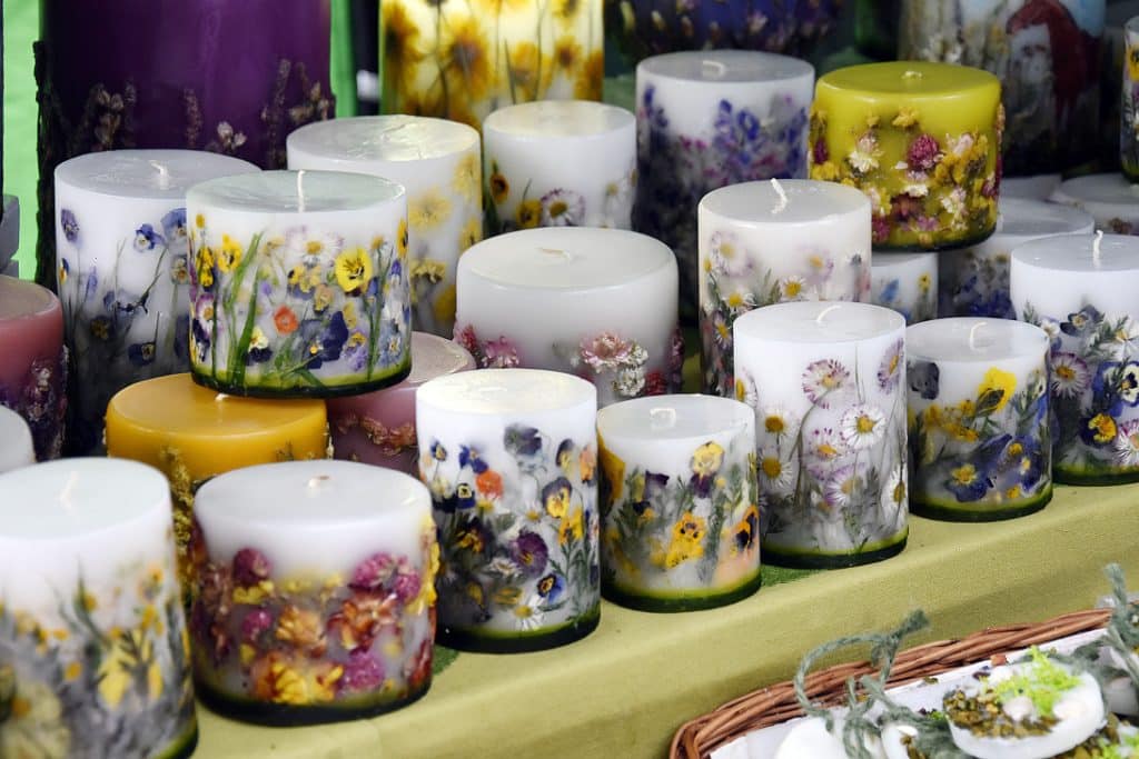 Świece ozdobione suszonymi kwiatami na stoisku targowym w Olsztynie.