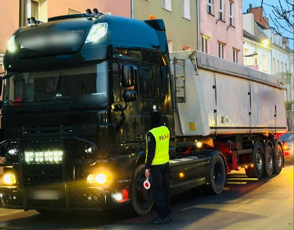 Policjant kontrolujący ciężar&oacute;wkę na ulicy w mieście wieczorem.