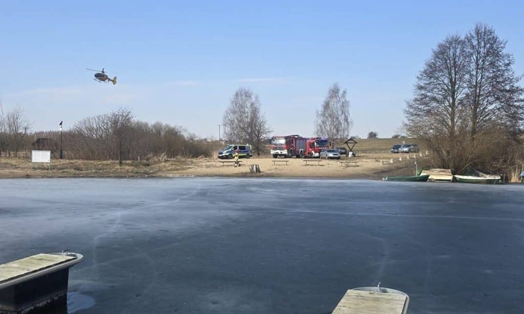 Akcja ratunkowa nad zamarzniętym jeziorem Linowo, widoczne służby i śmigłowiec.