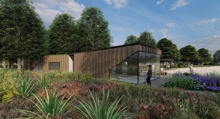 Nowoczesny obiekt rekreacyjny na plaży w Giżycku, otoczony zielenią i kwiatami, z dużymi oknami i drewnianą elewacją.