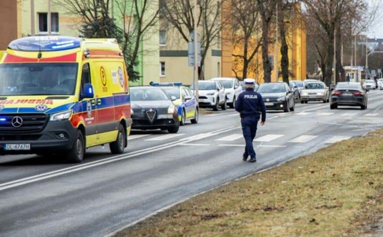 Policjant na ulicy Jagiellońskiej w Olsztynie, wok&oacute;ł pojazdy i karetka pogotowia.