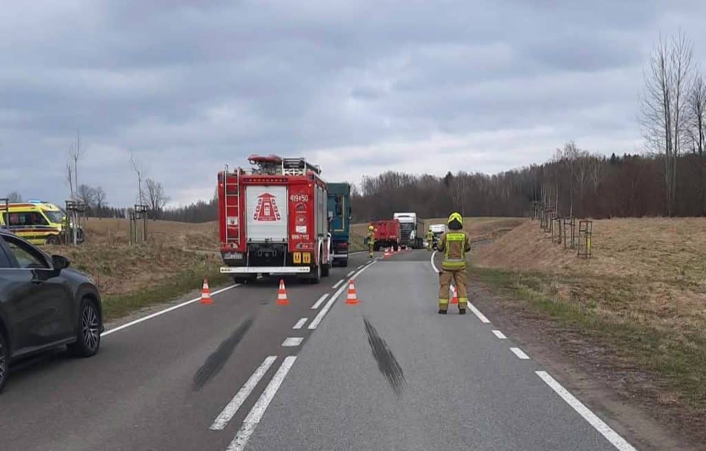 Widok na miejsce wypadku z udziałem ciężar&oacute;wki i motorowerzysty, służby ratunkowe na drodze.