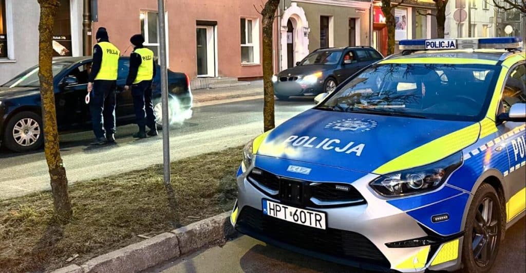 Policjanci przeprowadzają kontrolę na drodze, obok radiow&oacute;z na ulicy w regionie Warmii i Mazur.
